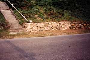 a newly completed section of a stone retaining wall with a mailbox sitting on the ledge