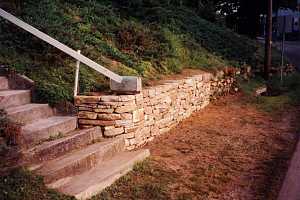a newly completed section of a stone retaining wall with a mailbox sitting on the ledge