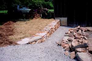 a stone retaining wall newly installed with fresh road stone in front of it