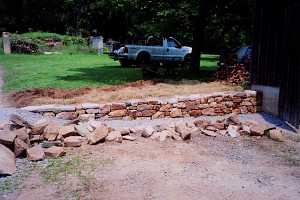 a stone retaining wall newly installed with fresh road stone in front of it