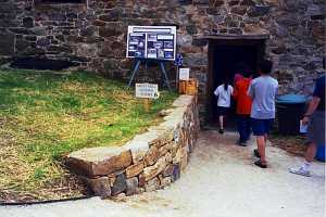 a stone retaining wall leading into a door. a sign on the hill reads grist mill guided tours