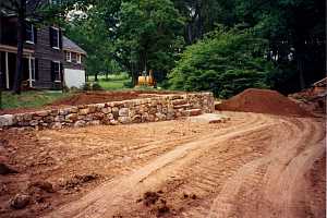 a yard that's been leveled with dirt and had a stone wall and stairs installed