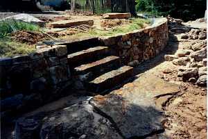 a stone wall and steps with a stone landing - in progress