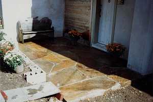 a stone patio with a bench and flowers on it