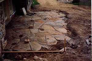 a dug-out section of yard where a stone patio is being installed