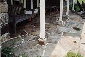 a stone patio with pillars and benches sitting on it