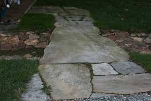 a stone walkway with grass growing between the stones