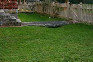 a large slab of stone connecting stone steps to the front walk by the fence and driveway