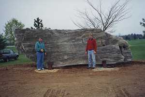 two men standing in front of a large stone