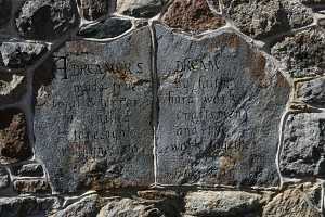 two stones inside a stone wall with an engraved message that reads: a dreamer's dream made true by faith, trial & error, hard work, skilled craftsmen, foresight, and the willingness to work together - Dreamer EDG 1982