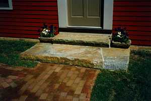 two stone steps leading down from a door to a brick walkway - after