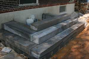 concrete steps being installed in front of a brick home