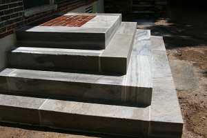 completed concrete steps leading up to a brick landing and front door