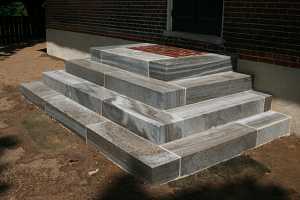 concrete steps leading up to a brick landing and front door