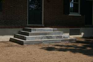 concrete steps leading up to a brick landing and front door