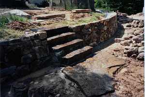 natural stone steps in between a natural stone retaining wall