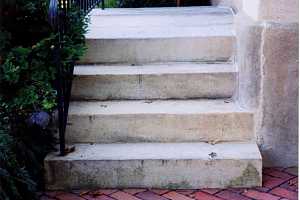 a brick walkway leading to stop steps with a black railing