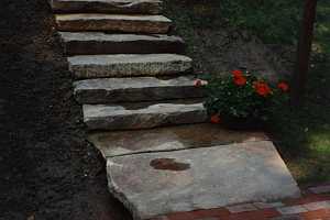 a brick walkway leading to stone stairs that take you up to a home on higher ground