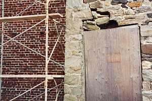 a cracked stone wall with scaffolding next to it