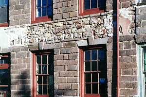 a repaired stone wall between two sets of windows on a stone building