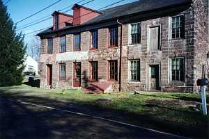 an old stone building with a new section of stone wall between the middle two sets of windows