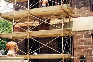 men on scaffolding repairing a damaged stone building