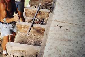 two men preparing the bottom layer of a new stone wall