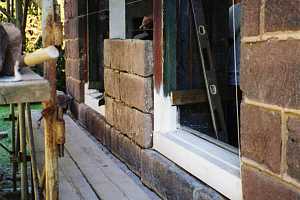 two window frames in a new section of stone wall