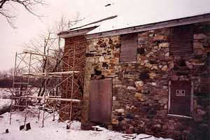 an old stone and brick building with boarded windows and cracked stone