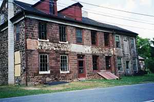 an old stone building with two new sections of stone walls between the 4 sets of windows