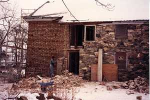 a man removing damaged stone from an old stone home