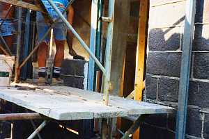 two men on scaffolding repairing a stone wall