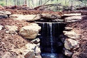 an installed stone waterfall on a dirt hill - after