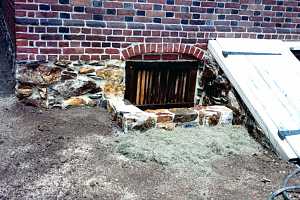 a stone window well next to a cellar door