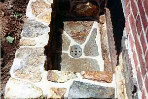 looking down in a natural stone window well with a drain in the middle