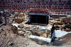 a newly installed natural stone window well with the area around it dug out