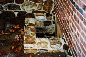 a newly installed natural stone window well at the corner of a stone and brick building