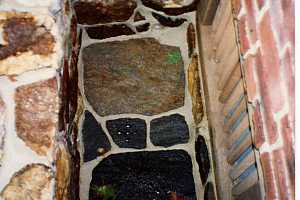 looking down in a natural stone window well with a drain in the middle