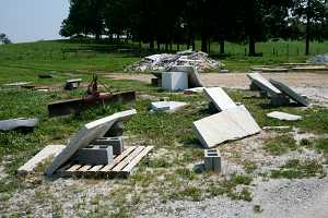 random cut stone and a plow in a grassy area